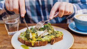 Man eating avocado toast with poached egg, close up